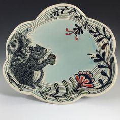 a decorative plate with a squirrel holding an acorn