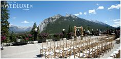 an outdoor wedding setup with chairs and flowers in front of a mountain backdrop for the ceremony