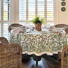 a dining room with wicker chairs and a round table covered in a white cloth