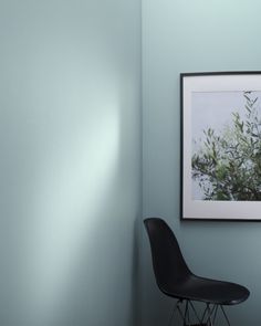 a black chair sitting in front of a framed photo on the wall next to a lamp