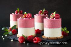 three small cakes with raspberries and mints on the top one is pink