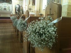 flowers are placed on pews at the end of a church aisle, with other pews in the background