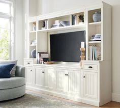 a white entertainment center with bookshelves and a large screen tv on it's side