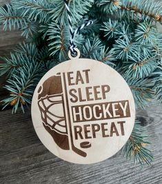 a wooden ornament that says eat sleep hockey repeat hanging from a pine tree