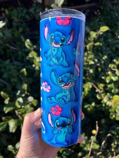 someone holding up a blue tumbler with stitching on it