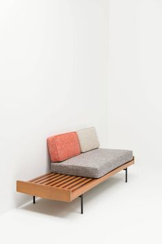 a couch that is sitting on top of a wooden bed frame with two different colored pillows