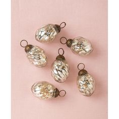 six glass ornaments on a pink background