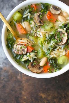 a white bowl filled with vegetable soup on top of a wooden table