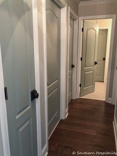 an empty hallway with white doors and wood floors