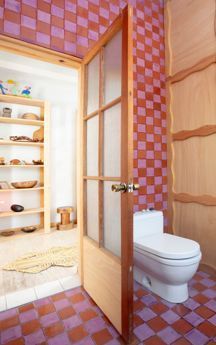 an open door leading to a bathroom with pink tiles on the walls