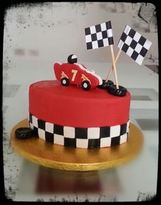 a birthday cake with a race car on top and checkered flags sticking out of it