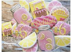 decorated cookies in the shape of lemonade and pink with yellow accents are displayed on a wooden surface