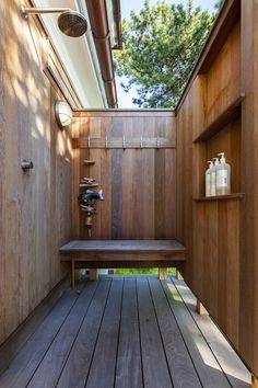 a wooden bench sitting under a window next to a shower head mounted faucet