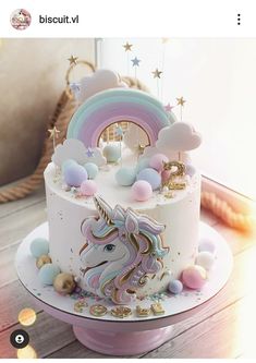 there is a white cake with a unicorn on it and rainbow decorations around the top