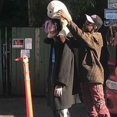 two people are standing on the street and one is holding a child's head