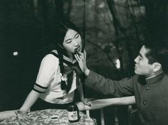 an old photo of a woman talking on the phone to a man sitting at a table