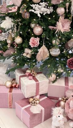 a christmas tree decorated with pink and gold ornaments, presents and other holiday decor items