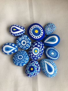 blue and white painted rocks arranged in the shape of an abstract flower on a white background