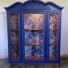 a blue china cabinet sitting on top of a hard wood floor next to a wall