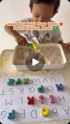 a little boy that is sitting at a table with some letters in front of him