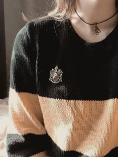 a woman wearing a black, yellow and white sweater with a crest on the front