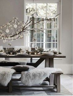 a dining room table with white fur chairs and a chandelier hanging from the ceiling