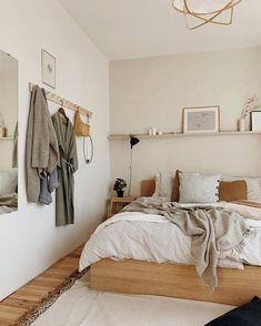 a bedroom with a bed, mirror and coat rack on the wall next to it