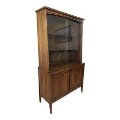 a wooden cabinet with glass doors on the top and bottom shelves, against a white background