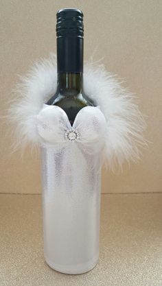 a wine bottle with a white feather bow on it and a diamond brooch in the middle