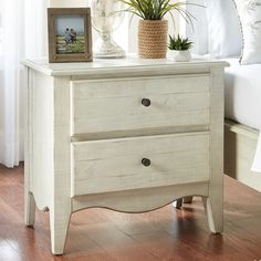 a white dresser with two drawers and a potted plant on it's top