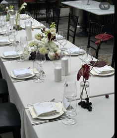 the table is set with white linens, place settings and flowers in vases