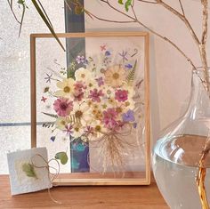 a vase filled with lots of flowers sitting on top of a table next to a card