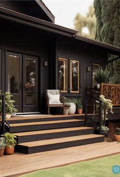 a black house with wooden steps and potted plants