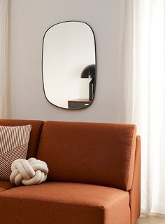 a couch with pillows and a mirror on the wall above it in a living room