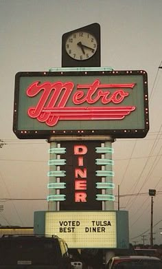 a neon metro diner sign with a clock on top