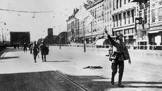 an old black and white photo of people walking down the street with their arms in the air