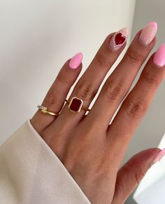 a woman's hand with pink and white nail polish on it, holding a gold ring