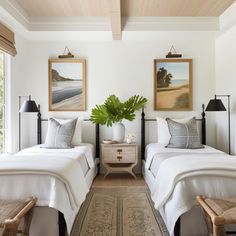 two twin beds in a bedroom with white walls and wood ceilinging, framed pictures on the wall