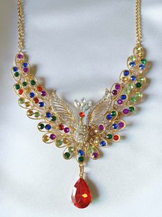 "Super fabulous necklace loaded with clear and multi-colored rhinestones is vintage beauty at its best. It has a clear stone peacock in the center. The sparkling rhinestones glow and are all present and original. Trimmed in shiny goldtone. Necklace has a 3 3/4\" drop in the center and measures approx 25\" long with convenient adjustable closure. Excellent condition both front and back, see second photo and this is a one-of-a-kind piece.   Packaged with care and ships in ONE business day. Spend $ Multicolor Crystal Rhinestone Necklace With Sparkling Stones, Multicolor Rhinestone Wedding Necklaces, Multicolor Rhinestone Necklaces For Weddings, Multicolor Crystal Rhinestone Necklace, Multicolor Crystal Rhinestone Costume Necklace, Multicolor Rhinestones Necklace For Wedding, Party Crystal Multi-stone Necklace, Crystal Multi-stone Necklace For Parties, Party Multi-stone Crystal Necklace