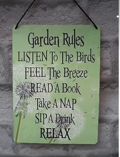 a green sign that says garden rules listen to the birds feel the breeze read a book take a nap sip a drink relax