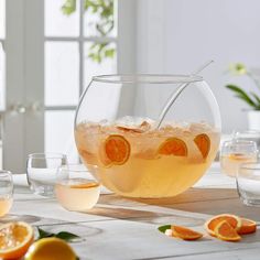 a pitcher filled with oranges and ice sitting on top of a table next to glasses