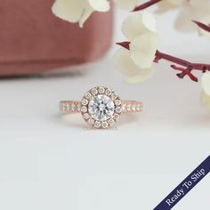 a rose gold engagement ring with an oval diamond center surrounded by small white flowers in the background