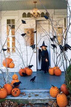 a woman standing in front of a door decorated with pumpkins and black birds on halloween day