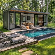 a small pool house in the middle of a lush green yard with lounge chairs around it