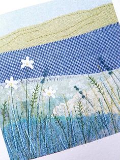 a close up of a piece of fabric with flowers and grass in the foreground