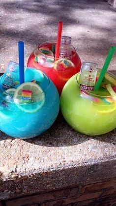 three different colored drinks sitting on top of a cement slab next to eachother