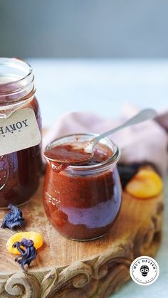 two jars filled with jam sitting on top of a wooden tray