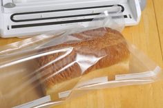 a loaf of bread wrapped in plastic sitting on a table next to a toaster