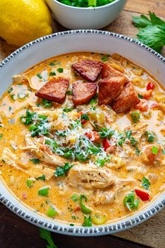 a white bowl filled with soup and meat on top of a table next to lemons