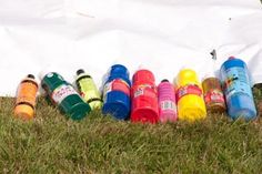 a group of children's shoes lined up on the grass in front of a white sheet